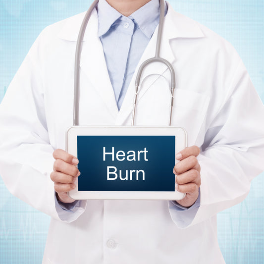 A healthcare professional in a white lab coat holds a tablet displaying the words "Heart Burn" against a light blue background with a subtle medical motif.