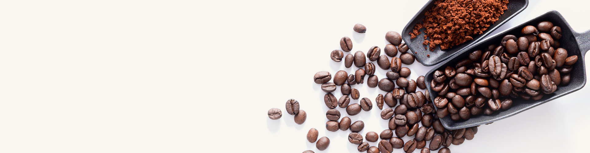 A spilled container of roasted coffee beans and another container of ground coffee on a white background, with some coffee beans scattered around.