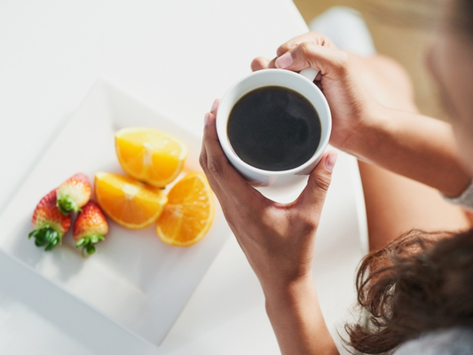 Cup of Alex’s Low-Acid Coffee surrounded by fresh berries and nuts