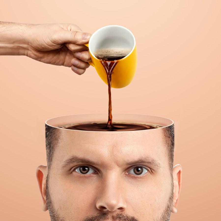 A hand pours coffee from a yellow cup into the open top of a man's head, which appears to be a bowl filled with dark liquid, set against a soft peach background.