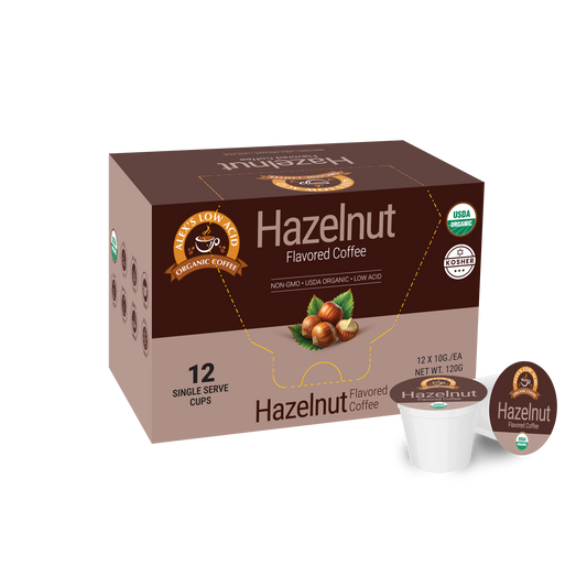 A box of Alex's Low Acid Organic Coffee™ Single Serve Flavored Cups - Hazelnut displays hazelnut imagery and organic and kosher certifications, with a heartburn-friendly, low acid pod from Alex's Low-Acid Organic Coffee placed in front.
