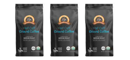 Three black bags of Alex's Low-Acid Organic Coffee™ - Half Caff Fresh Ground (12oz) from Alex's Low Acid Coffee offer a medium roast that's low acid, organic, non-GMO, and herb-organic with a coffee cup icon and bold orange-blue text on the front.