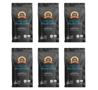 Six bags of Alex's Low-Acid Organic Coffee™ - Half Caff Fresh Ground (12oz) by Alex's Low Acid Coffee are arranged in two rows of three. Each sleek black bag is medium roast, non-GMO, organic, and features white and blue text.
