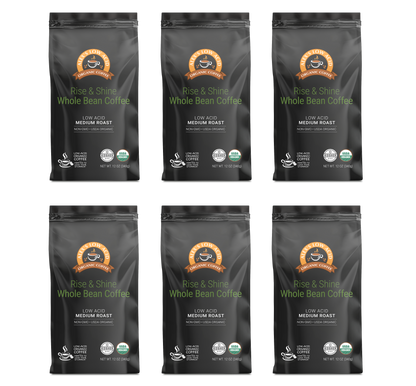 Six bags of Alex’s Low-Acid Organic Coffee™ - Rise and Shine Whole Bean (12oz) by Alex's Low Acid Coffee, with orange and green labels, are arranged in two rows on a white background.